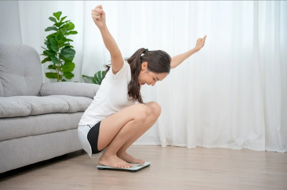 Woman celebrating her weight loss journey at home